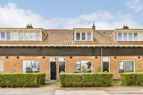 A Brick House With Hedges In Front Of It Stock Photo By Pro Creator